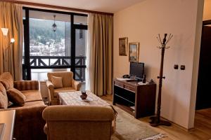 バンスコにあるCozy Suite in 5* Luxury Spa Hotelのリビングルーム(ソファ、テーブル、テレビ付)