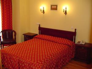 a bedroom with a bed with a red comforter at Hotel Europa in Ploieşti