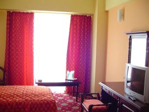 1 dormitorio con 1 cama y una ventana con cortinas rojas en Hotel Europa, en Ploieşti