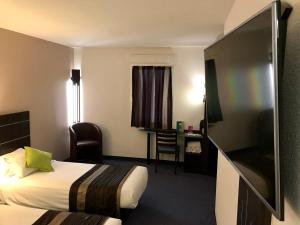 ドル・ド・ブルターニュにあるKyriad Dol-de-Bretagneのベッドとデスクが備わるホテルルームです。