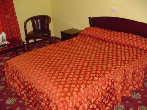 a bedroom with a bed with a red comforter and a chair at Hotel Europa in Ploieşti