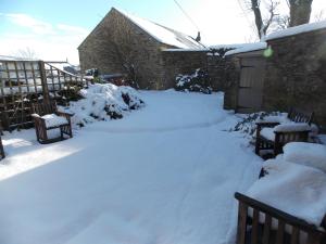 a yard covered in snow with two benches at Hilltop Cottage, Barnard Castle in Barnard Castle