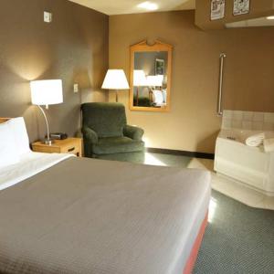 Habitación de hotel con cama y silla en Boarders Inn and Suites by Cobblestone Hotels - Fayette, en Fayette