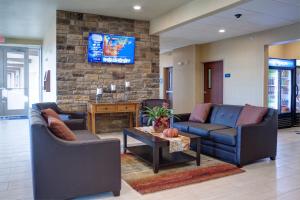 a lobby with two couches and a tv on a brick wall at Cobblestone Hotel and Suites - Jefferson in Jefferson
