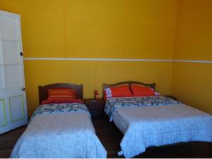 two beds in a room with yellow walls at Hospederia Taltal in Taltal