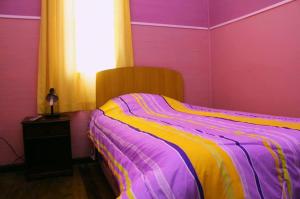 Cama rosa y amarilla en una habitación en Hospederia Taltal, en Taltal