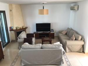 a living room with couches and a flat screen tv at villa cinco palmas in Almerimar