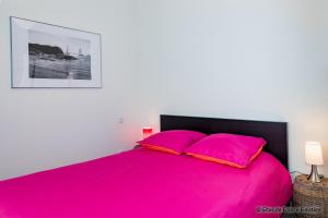 a bedroom with a pink bed with two pink pillows at La maison du port in Plougasnou