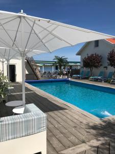 ウレグルンドにあるStrandhotelletのスイミングプール(パラソル、テーブル、椅子付)