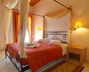 a bedroom with a canopy bed with a red comforter at Acropole Delphi City Hotel in Delphi