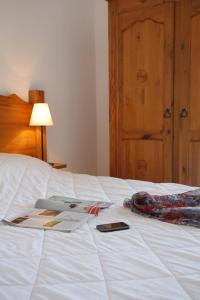 a bed with a book and a cell phone on it at La Pradella in Bolquere Pyrenees 2000