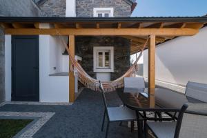 eine Terrasse mit einer Hängematte sowie einem Tisch und Stühlen in der Unterkunft Casa do Leme in Arco da Calheta