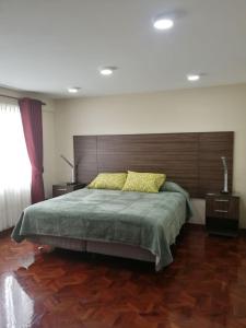 a bedroom with a large bed with a wooden headboard at Miraflores Apart in La Paz