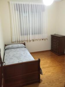 a bedroom with a bed and a dresser and a window at La Nogalera in Nueva de Llanes