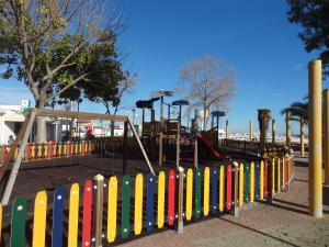 un parque infantil con una valla colorida y una zona de juegos en Fisherman's Palace, en Olhão