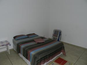 ein Bett mit einer bunten Decke auf einem Zimmer in der Unterkunft Guerreiro Sui­tes in Boicucanga