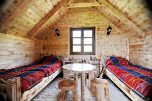 two beds and a table in a wooden room at Komovi Eko Katun Martinovica 1750 in Kolašin