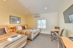 1 Schlafzimmer mit 2 Betten, einem Tisch und einem Schreibtisch in der Unterkunft Motel Grande in Tamworth
