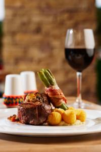 a plate with a steak and a glass of wine at Hotel Waya Guajira By OxoHotel in Albania