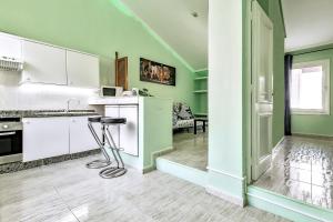 a kitchen with green walls and white cabinets and a stool at Apartment Calle Madrid in Adeje