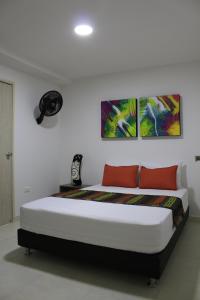 ein Schlafzimmer mit einem Bett mit drei Gemälden an der Wand in der Unterkunft Hotel Pereira 421 in Pereira