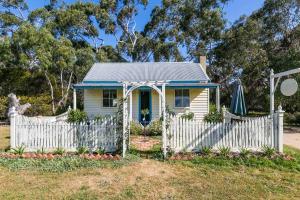 una pequeña casa blanca con una valla blanca en Freshwater Creek Cottages & Farm Stay, en Torquay