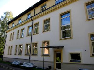 a white building with two benches in front of it at Hotel Vilmaja in Riga