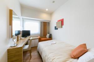 a hotel room with a bed and a desk with a computer at Sotetsu Fresa Inn Nagano-Zenkojiguchi in Nagano