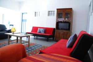 a living room with red furniture and a tv at Mr Pell's House Self-Catering Accommodation in Jeffreys Bay