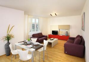 ein Wohnzimmer mit einem Sofa, einem Tisch und Stühlen in der Unterkunft Salvator Superior Apartments in Prag