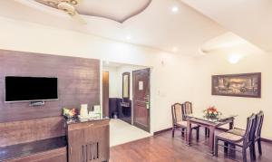 a dining room with a table and a television on a wall at Hotel Grand Legacy in Dehradun