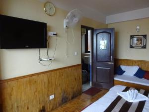 a room with a tv on the wall and a bed at Jain Group Hotel Royal Residency in Gangtok