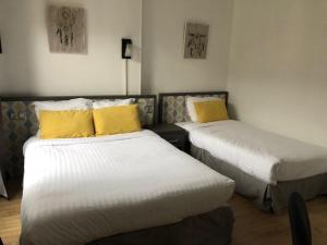 ルーアンにあるレ イニシエの黄色い枕付きのベッド2台が備わる客室です。