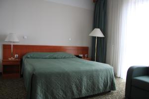 a bedroom with a bed and a chair and a window at Hotel Aquapark Žusterna in Koper