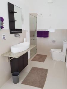 a white bathroom with a sink and a toilet at Gästehaus Isabella in Beruwala