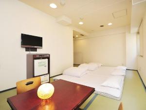 a room with two beds and a table and a tv at Hotel Paco Obihiro Chuo in Obihiro