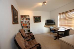 a living room with two chairs and a table and a television at 2 The Rocklands in Birkenhead