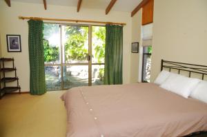 a bedroom with a bed and a large window at LaMaison de Shines, 13 Dulconghi Street in Crescent Head