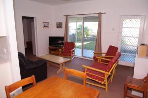 a living room with chairs and a tv and a table at Fleur Cottage, 7 Willow Street in Crescent Head