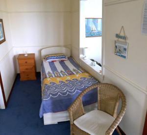 1 dormitorio pequeño con 1 cama y 1 silla en Lorikeet Retreat, 11 Hodgson Street, en Crescent Head