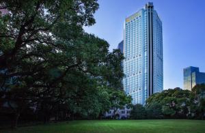 a park with trees and a tall building at The Kunlun Jing An in Shanghai