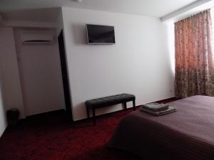 a bedroom with a bed and a stool and a television at Colosseum Residence in Bucharest