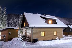 a house covered in snow at night with lights on at Chata Holiday Jasná in Belá