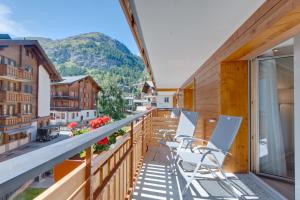 a balcony with chairs and a view of the mountains at Hotel Aristella Swissflair in Zermatt