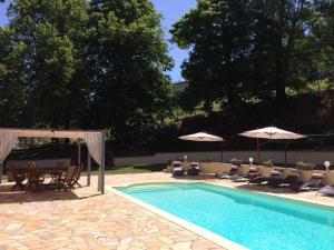 una piscina con sillas, mesas y sombrillas en La Maison du Parc, en Yzeron