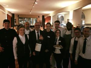 un grupo de personas posando para una foto con una botella de vino en Villa Behr, en Wendlingen am Neckar