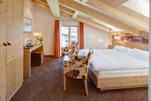 a bedroom with a bed and a desk and a chair at Hotel Aristella Swissflair in Zermatt