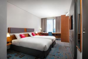 a hotel room with two beds and a television at Ibis Ambassador Myeongdong in Seoul