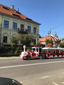 a red and white train traveling down a street at Pensiunea Gasthaus Alte Post in Sighişoara