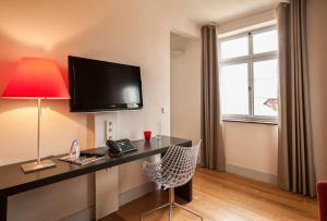 a room with a desk with a television and a chair at Villa Behr in Wendlingen am Neckar